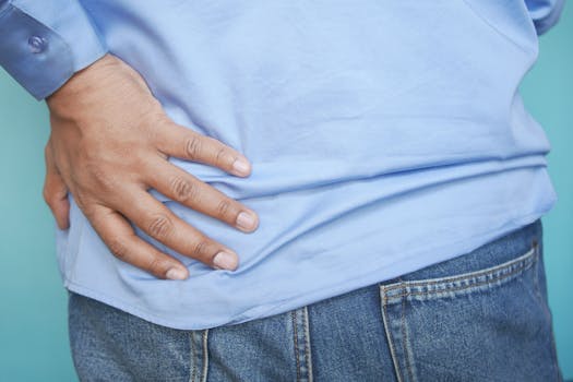 A person in a blue shirt and jeans clutching their hip, possibly indicating pain.