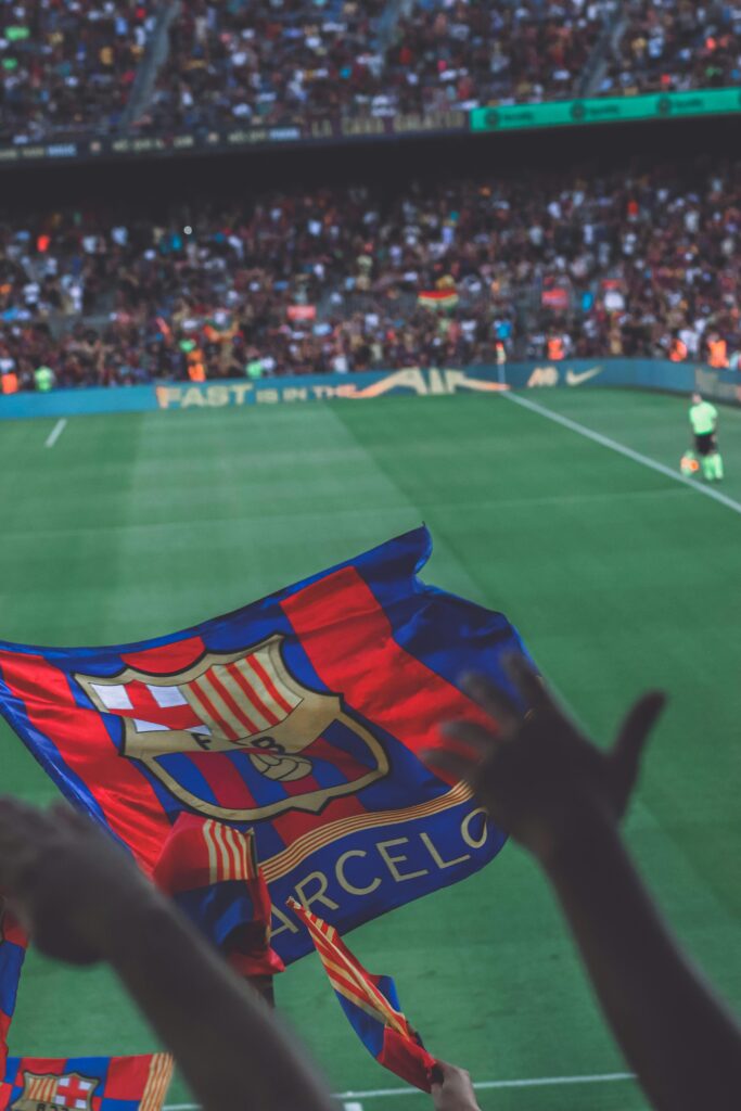 Fans waving flags during a vibrant soccer match at a stadium in Barcelona.