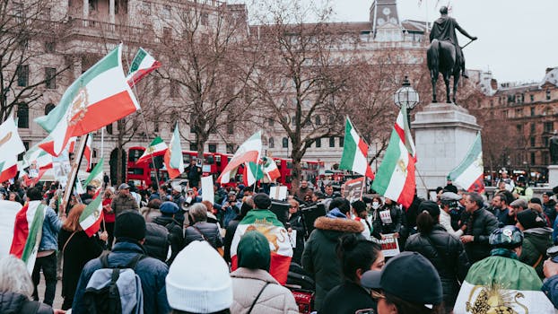 Crowd protesting with Iranian flags in a vibrant city square.
