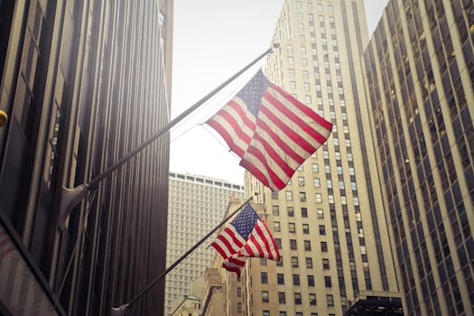 American flags waving among New York skyscrapers, showcasing urban patriotism.