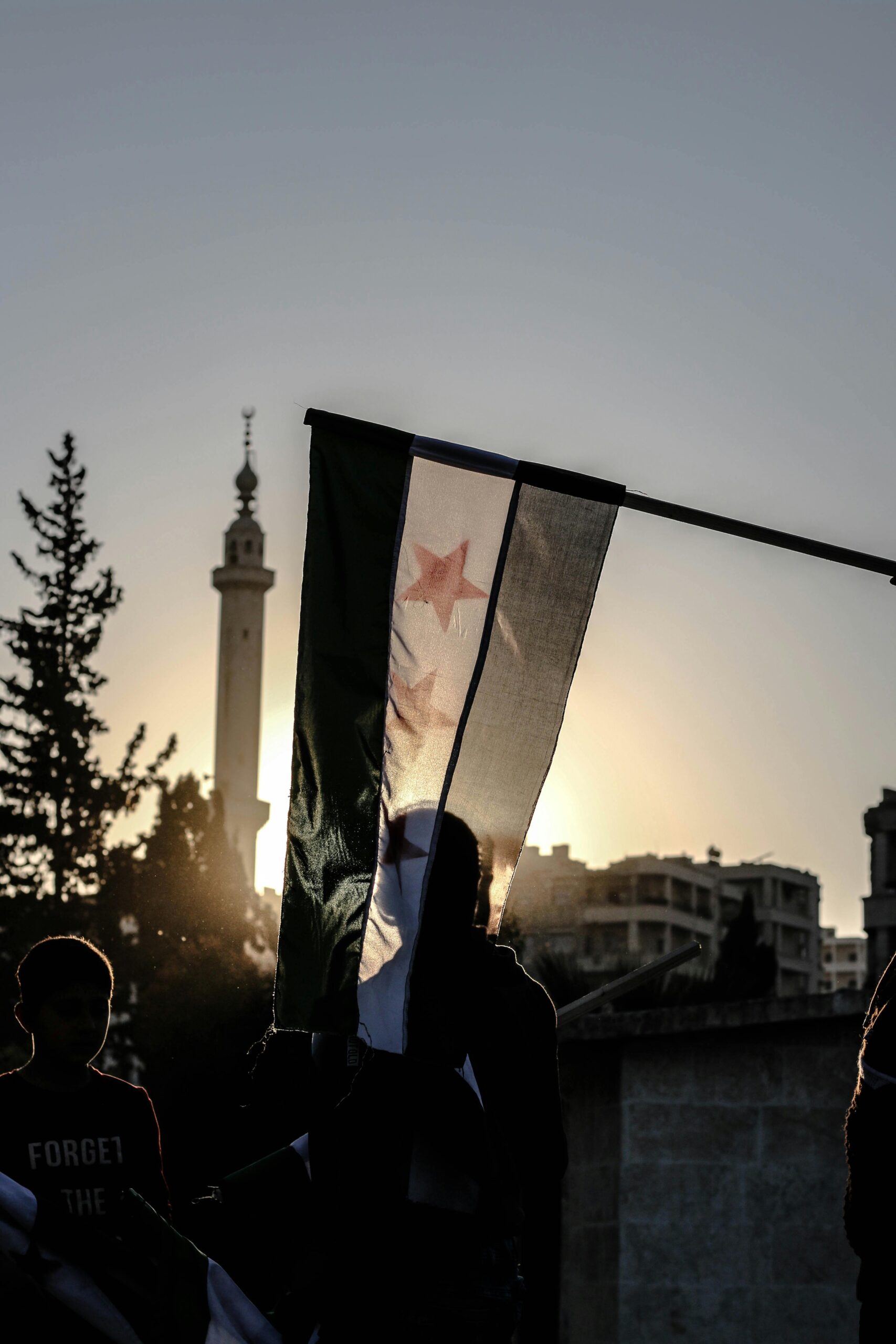 A powerful silhouette of a Syrian flag against a sunset backdrop in Idlib.
