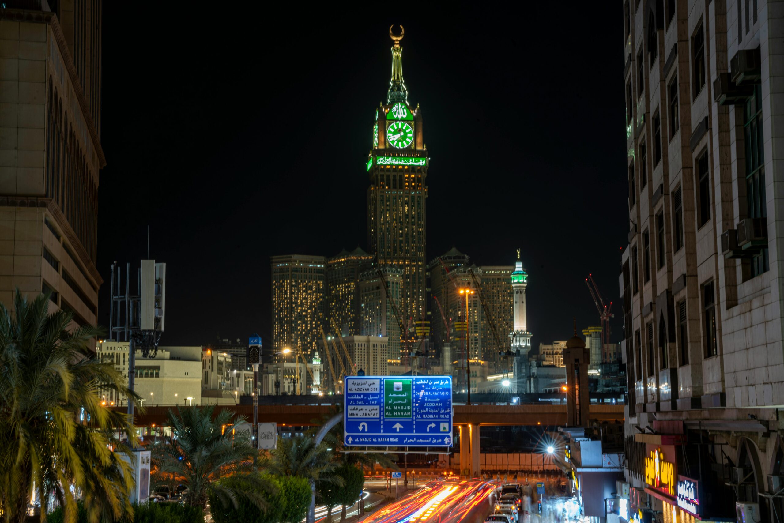 Illuminated view of Makkah Royal Clock Tower at night in the cityscape.