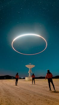 Three people observe a glowing ring above a radio telescope under a starry sky.
