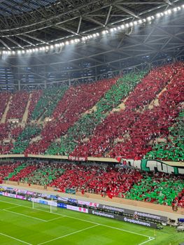 A packed stadium with fans in red and green, creating an energetic ambiance during a soccer match.