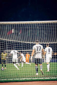 Dramatic scene of a competitive soccer match at night, capturing player dynamics and action.