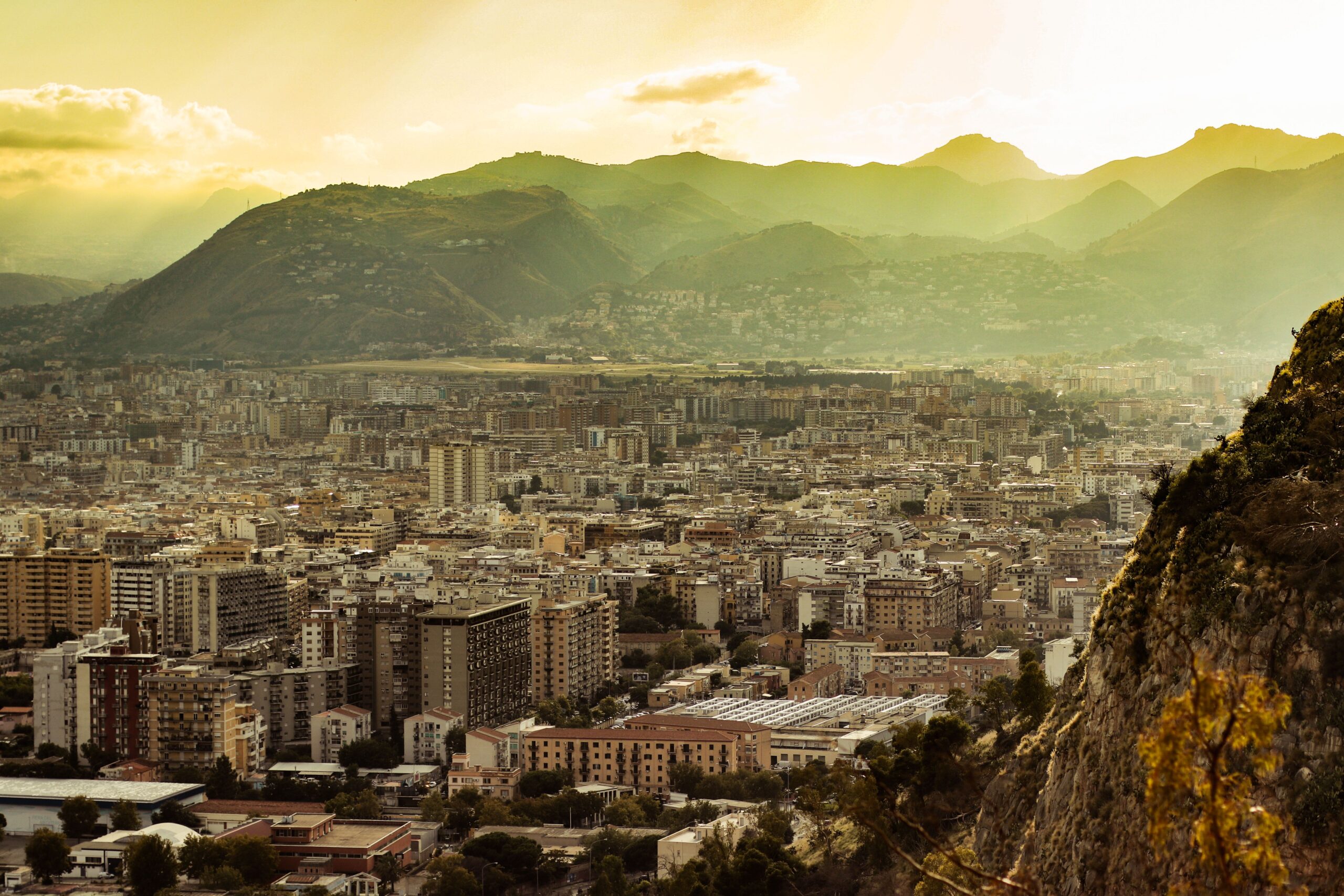 Breathtaking view of Palermo, Italy during sunrise, featuring cityscape and surrounding mountains.