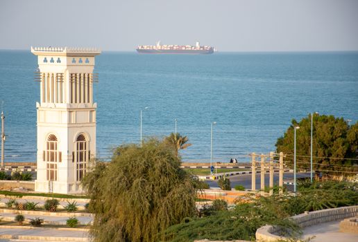Scenic view of Qeshm Island's coastline featuring a traditional wind tower and the ocean horizon.