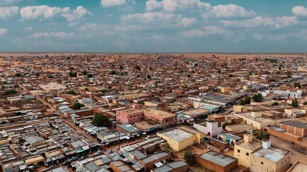 Aerial panorama of a sprawling desert townscape with flat-roofed buildings under a bright sky.