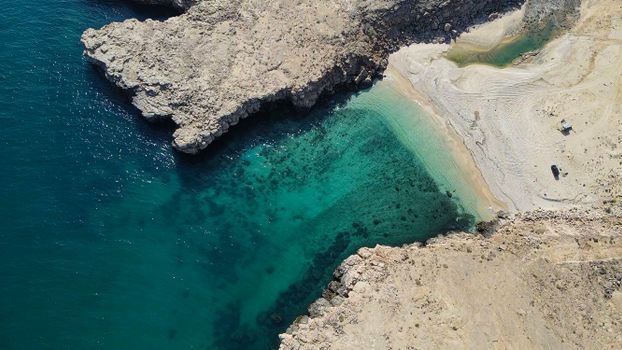 Explore the hidden beauty of Dhofar, Oman with this breathtaking aerial shot of a secluded beach cove.